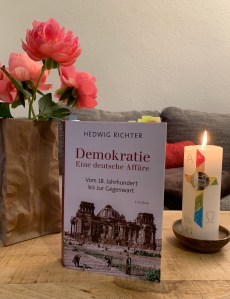 Das Buch mit Pfingstrosen und Osterkerze.