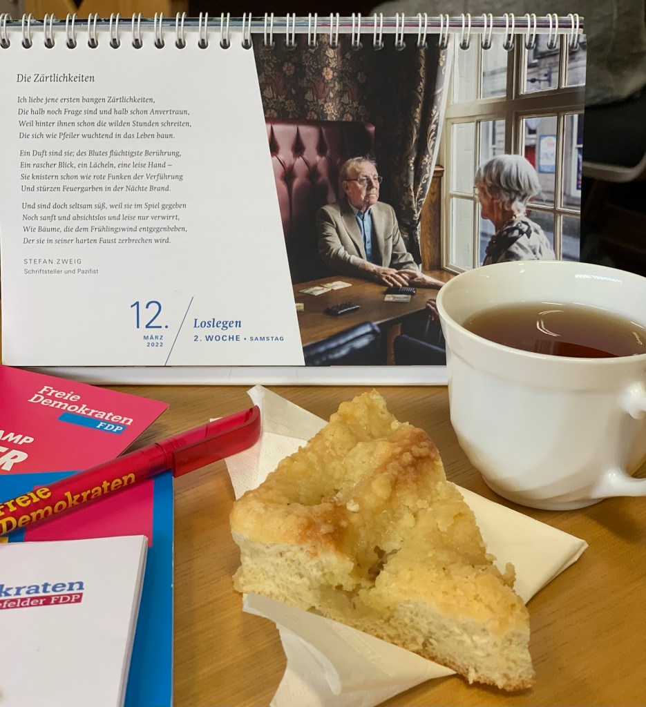 Ein Stückchen Butterkuchen auf einer Papierserviette. Links daneben Papiere und Kuli mit FDP-Emblemen. Rechts daneben eine Tasse Tee ohne Untertasse (gab keine). Dahinter der Fastenkalender von 7 Wochen Ohne.