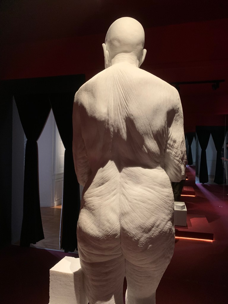 Jago, Venus, Rückenansicht: Als alte. faltige und kahlköpfige Frau.