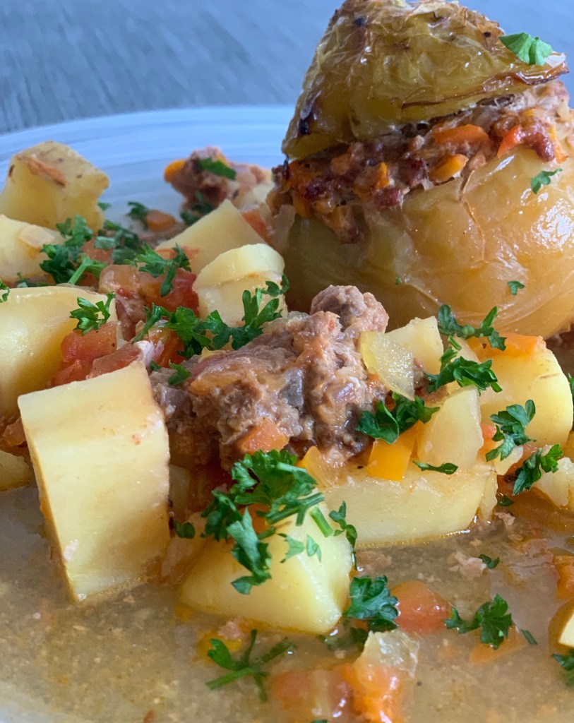 Grüne (Zuchtfarbe, also nicht unreif) gefüllte Tomate, angerichtet mit gewürfelten Kartoffeln, Sud und Petersilie überstreut.