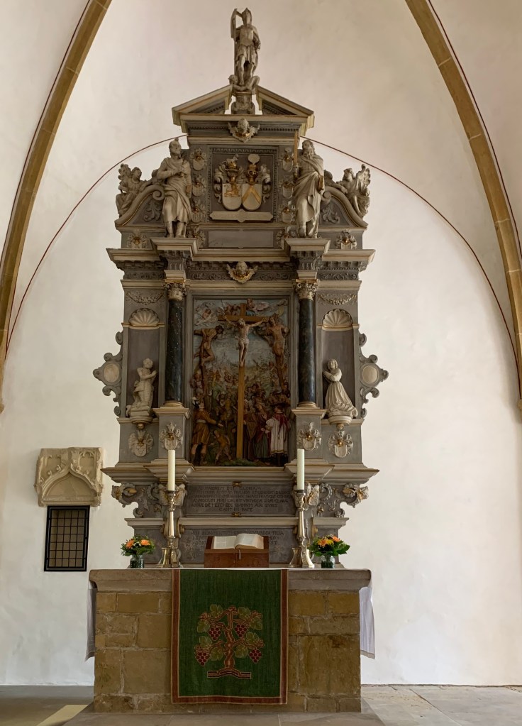 Historischer Altar der genannten Kirche mit künstlerischem Holzaufbau, Altarkerzen und Bibel.