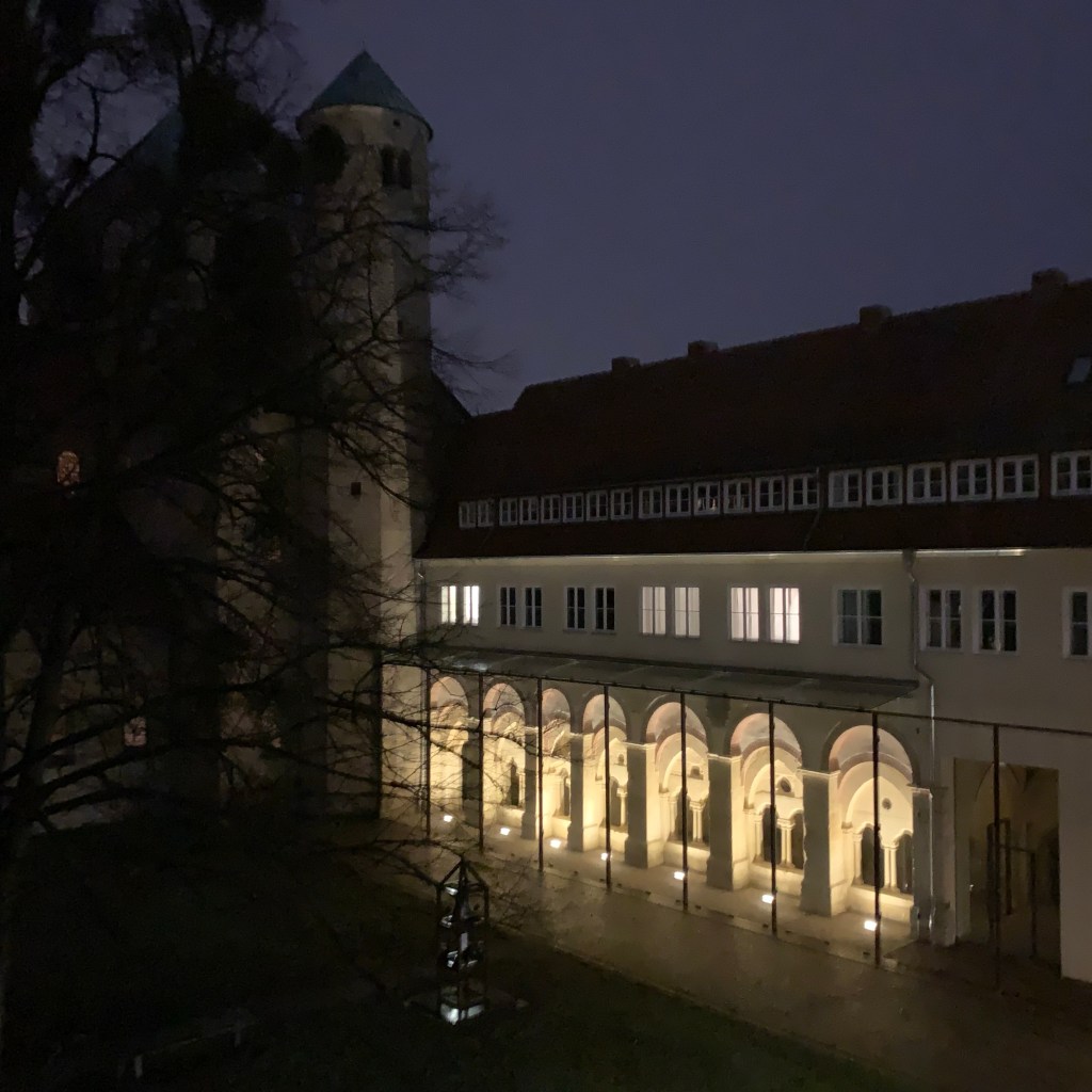 Nächtlicher Blick aus dem Dachfenster auf den Garten und den beleuchteten Kreuzgang des Michaelisklosters, Hildesheim.