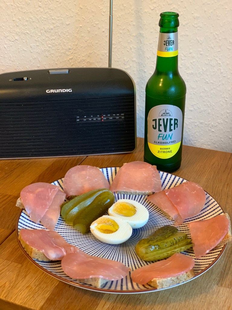 Der Teller mit dem beschriebenen Abendbrot und die Flasche Jever fun Zitrone vor dem Küchenradio.