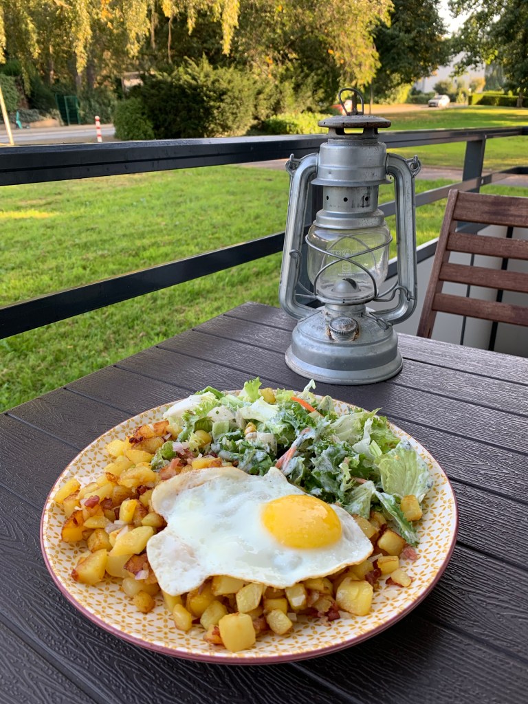 Kasserollenkartoffeln wie beschrieben mir Salat und Spiegelei auf einem Teller und auf dem Balkon serviert.