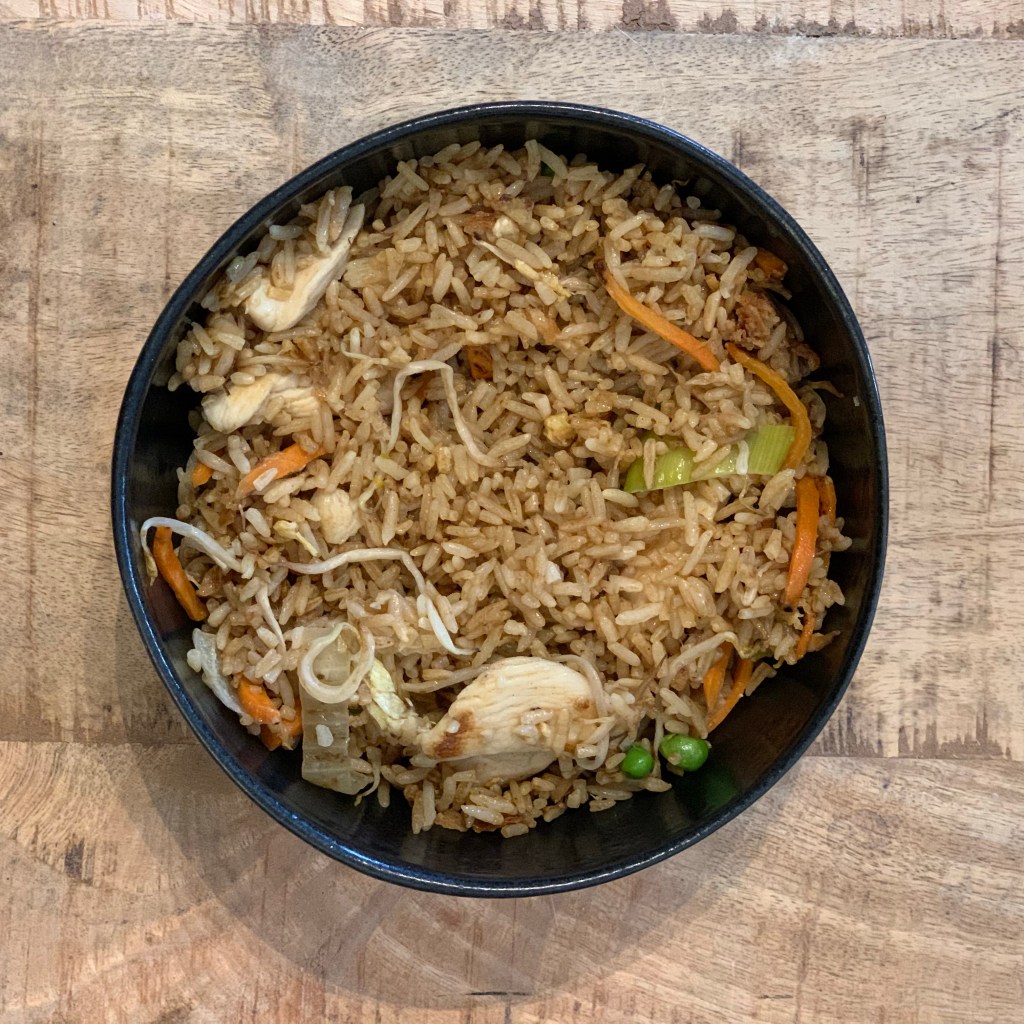 Bratreis mit Hühnerfleisch in einer schwarzen Schale.