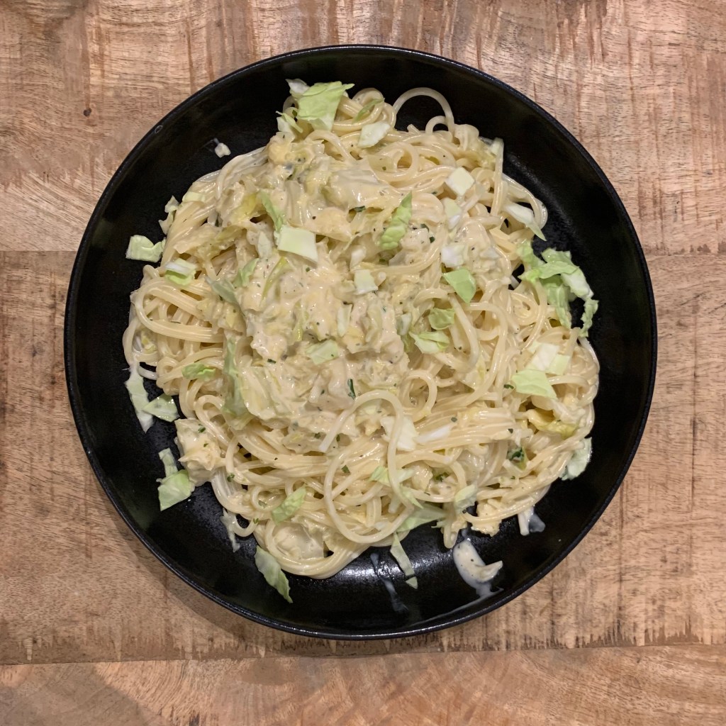 Spaghetti mit Käse-Wising-Sauce auf einem schwarzen, tiefen Teller.