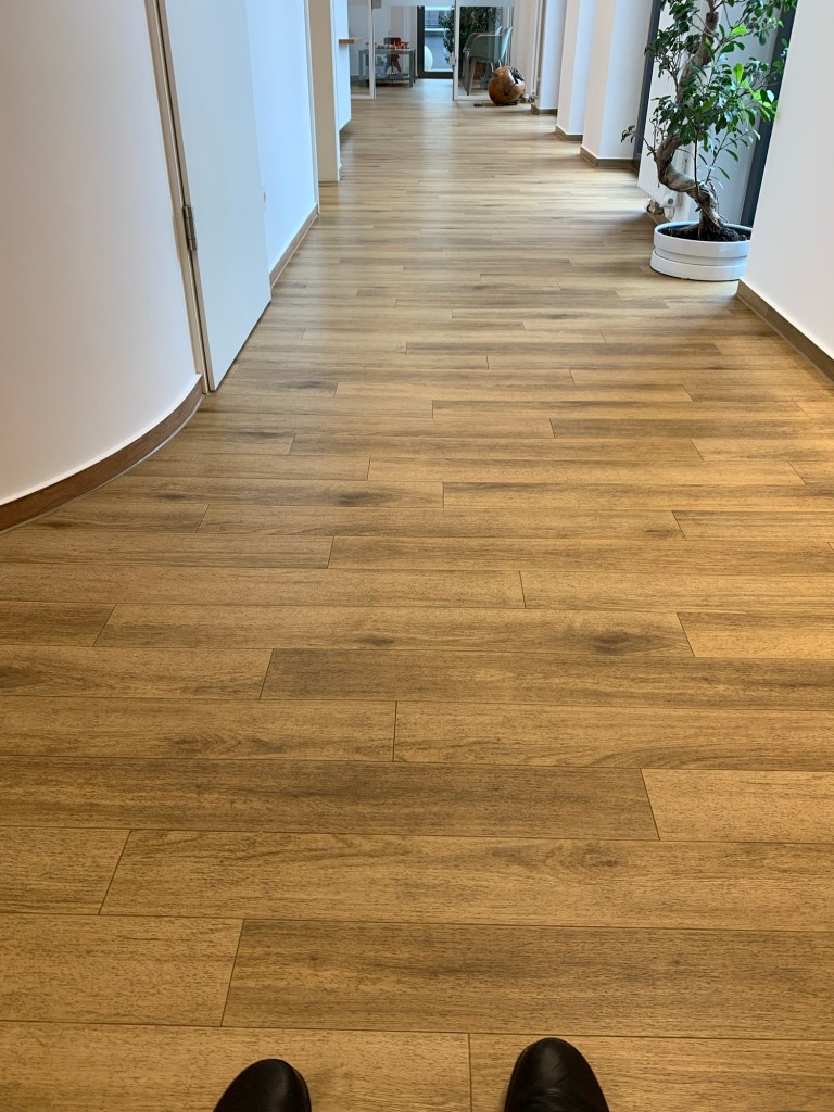 Der lange Flur in der Praxis der Ärztin, von den Wartestühlen vor dem Behandlungsraum, die man nicht sieht, sondern nur meine Schuhspitzen bis zum eigentlichen Wartezimmer.