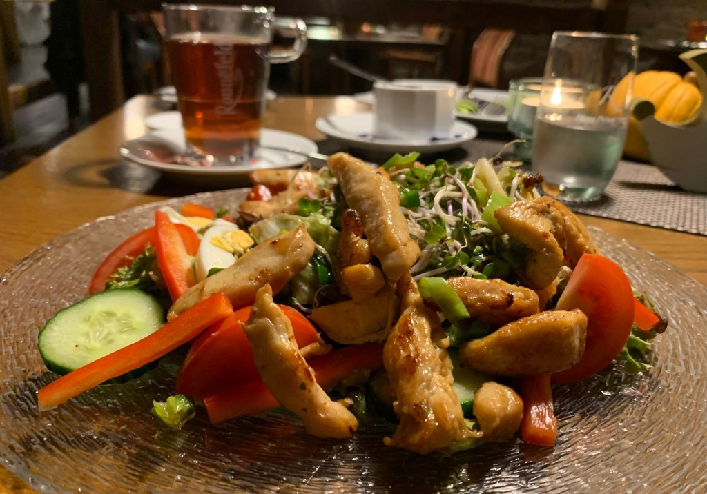 Der Salat auf einem ribbeligen Glasteller, im Hintergrund ein Glas Tee und ein Glas Wasser (ohne KribbelI und was auf Restauranttischen so herumsteht.
