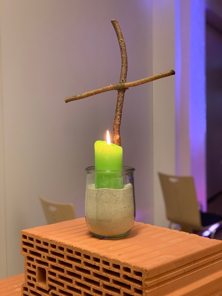Bei beginnender Abenddämmerung Blick über den französischen Balkon des Krankenzimmers auf die herbstlichen Wälder, die Infrastruktur dazwischen sieht man erst im Dunkeln. Rechts im Bild die zeigende Hand der Bettnachbarin mit roten Fingernägeln. Unbeabsichtigt tippt der Zeigefinger fast die Kuppel der Alten Kapelle an.
