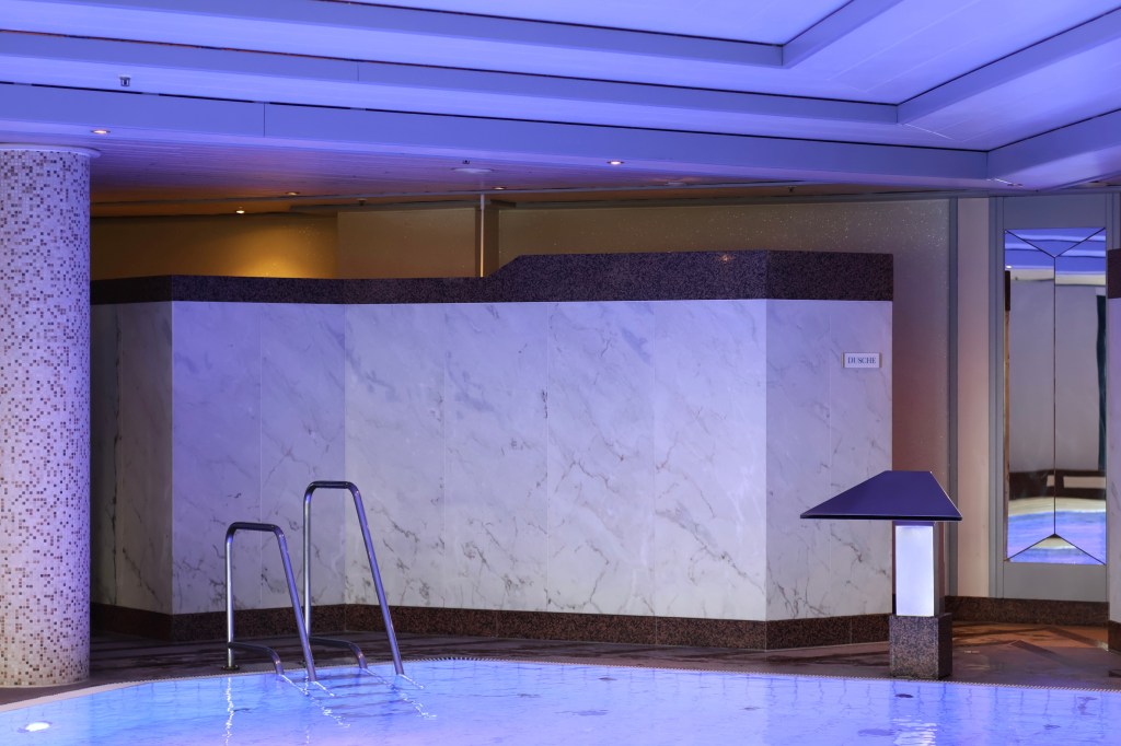 Foto des Hotelpools, der in lavendelfarbenes Licht getaucht ist.