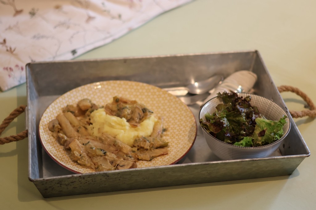Das beschriebene Mittagessen auf einem Teller und im Schälchen auf einem Tablett, das auf meinem Bett steht. Man sieht eine Ecke vom Kopfkissen.