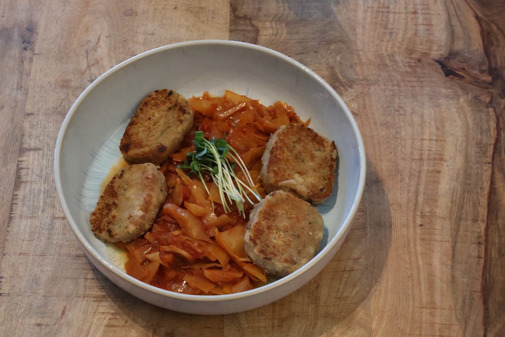 Das Mittagessen wie beschrieben in einer großen Schale. In der Mitte das Kraut mit einem Sträußchen Radieschensprossen als Deko und an den Seiten jeweils zwei Scheiben Serviettenknödel.